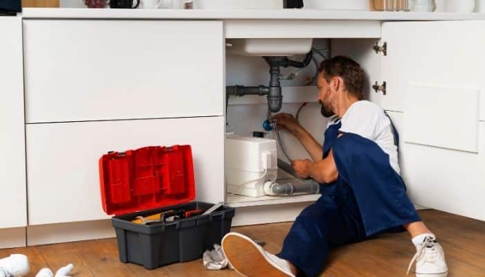 Plumber working under a kitchen sink